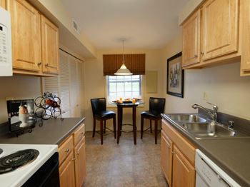 A white refrigerator stands in a kitchen with wooden cabinets and a white stove. at Painters Mill Apartments, Owings Mills, MD, 21117